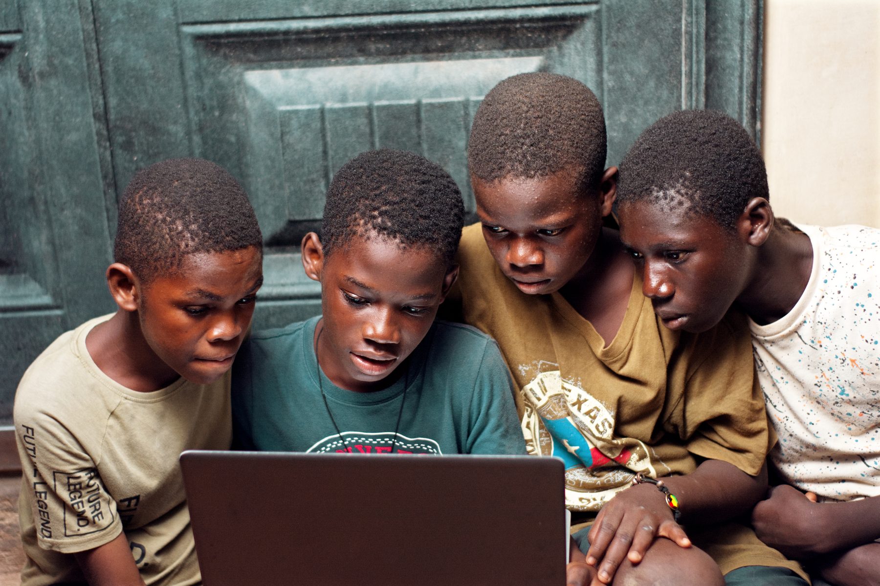 A group of young people in Ghana enjoying access to a laptop at home